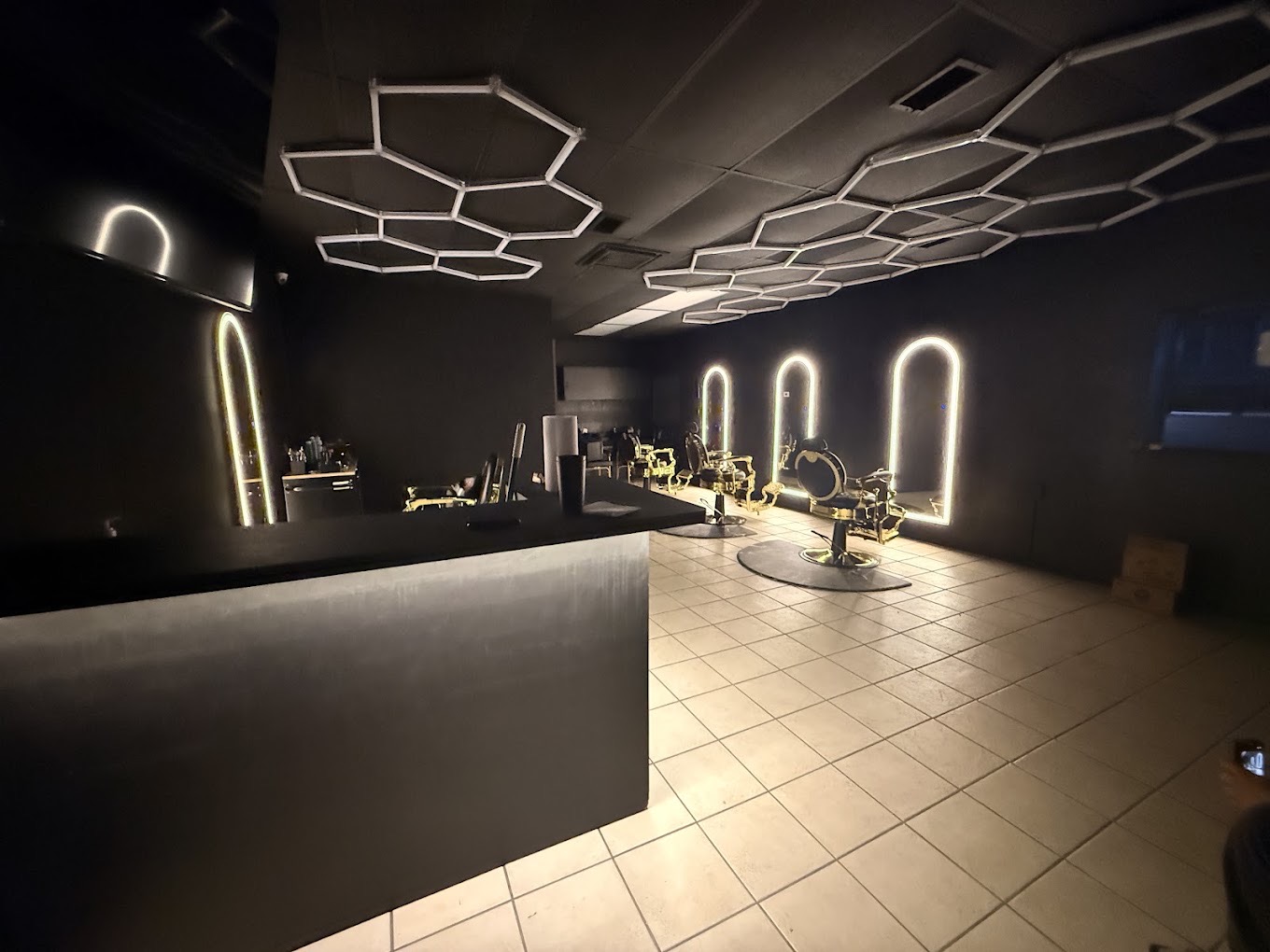 Inside OMI Barbershop &mdash; gold chairs, arched mirror lights and honeycomb ceiling lighting